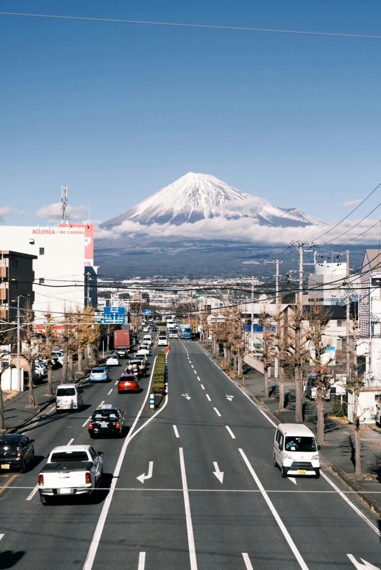 Urban street in Fuji, Japan, with the iconic Mount Fuji in the background, under a clear blue sky.